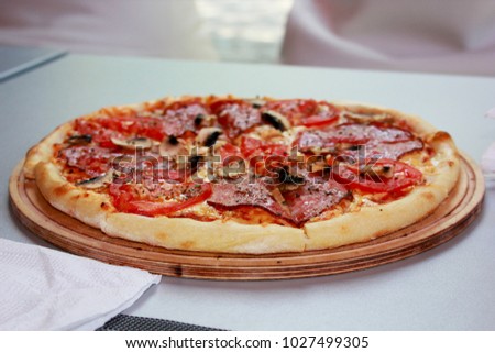 
Pizza on a round wooden plate cut into pieces