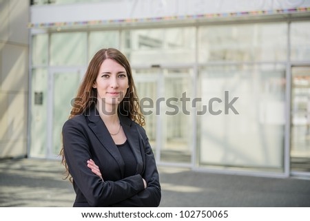 Young smiling business woman - portrait on building glass background