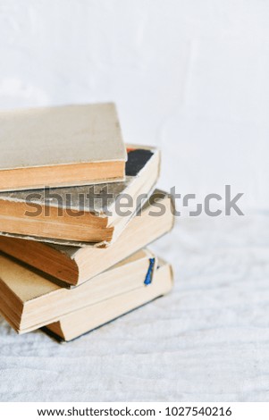 a stack of old battered books, and upstairs, an open book on a white background, copyspace