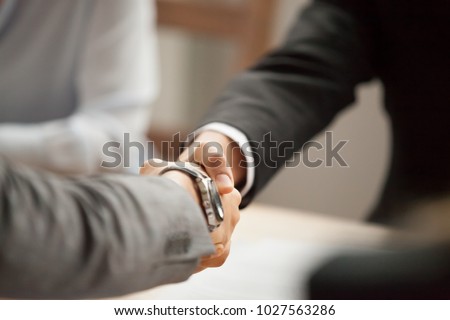 Two businessmen in suits shaking hands at group meeting, partners handshaking at negotiations making deal or signing contract, thanking for help support, welcome greeting handshake concept, close up Royalty-Free Stock Photo #1027563286