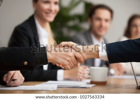 Hands of senior and young businessmen shaking at group meeting, two partners of different age handshaking making agreement or good deal, concluding contract help support concept, close up view Royalty-Free Stock Photo #1027563334