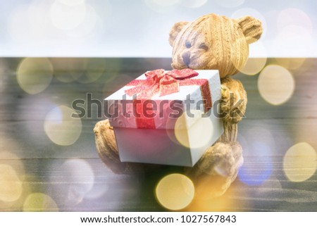 Decoration of brown teddy bear hold gift box on black textured wood and light bokeh with copy space for text.  Valentines day holiday celebration. Online commercial. Double exposure.