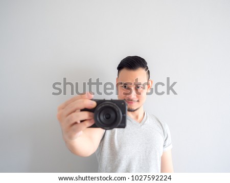 Asian man is holding a mirrorless camera and try to take a photo.