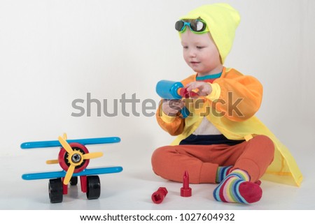 Funny kid in sunglasses with glasses and a bright ski suit. A child plays with a toy airplane representing himself as a pilot. The boy is happy spending vacations in the village. Winter Joys and Snow