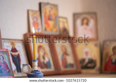 A burning candle against the background of orthodox icons