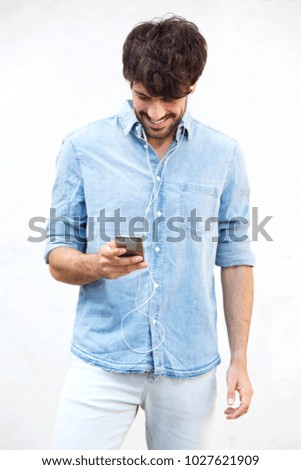 Portrait of young man with listening to music with mobile phone and earphones