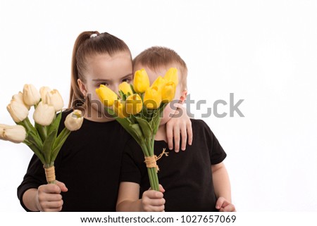 brother and sister in black blouses holding tulips in their hands. Shooting in the studio on a white background