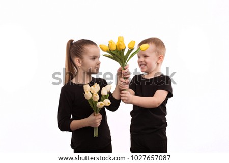 brother and sister in black blouses holding tulips in their hands. Shooting in the studio on a white background