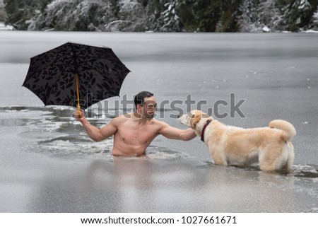 Bizarre picture of a man holiding an umbrella and petting a dog in a frozen lake. Taken in Alice Lake, Squamish, North of Vacouver, BC, Canada.