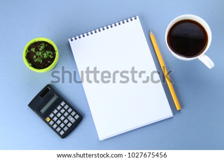 Top view image of open notebook with blank pages and coffee on blue background, ready for adding or mock up. Still life, business, office supplies or education concept