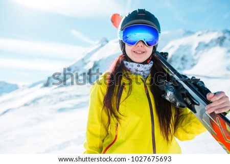 Picture of sports girl wearing helmet, mask with skis on her shoulder