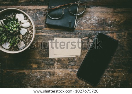 Mock-up of two blank craft business cards, smartphone, eye glasses, headphones on natural brown authentic wooden desk. Business empty mock-up background for message writing.Top view concept