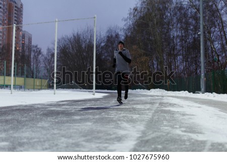Image of athlete in black sports clothes running through winter