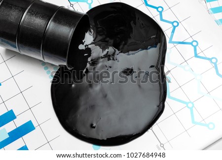 Crude oil spilled from container on financial graphs. Business concept. Top view. Royalty-Free Stock Photo #1027684948