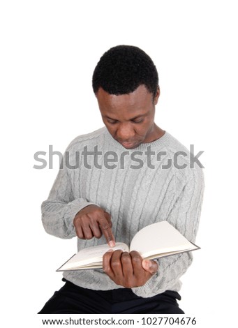 A handsome serious young African American man sitting and holding
his book and pointing at it, isolated for white background
