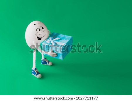 Funny miniature easter egg boy holding present box against colorful background. 