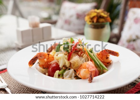 Starter with fried shrimps and raw vegetables, light summer dish, restaurant table outdoors