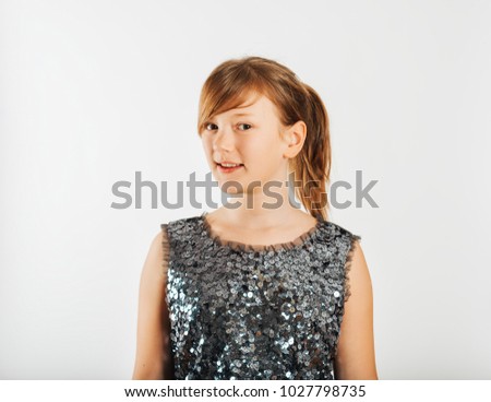 Studio shot of cute kid girl taken on white background, wearing sequin party dress