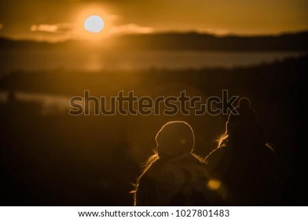 Two girls on mountain watching sunset