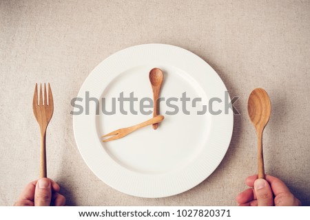 white plate with spoon and fork, Intermittent fasting concept, ketogenic diet, weight loss,  food crisis, restaurant and cafe reopening post covid-19 coronavirus pandemic Royalty-Free Stock Photo #1027820371