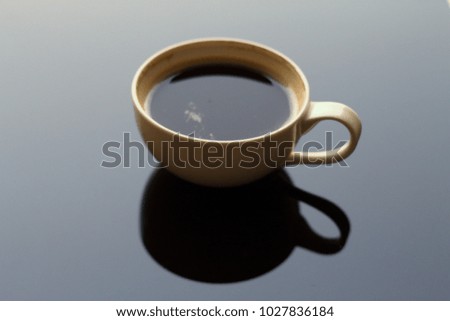 Cup of depleted black coffee with its shadow