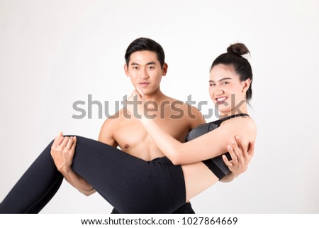 Happy young fitness  man carrying his girlfriend after Training. Fitness and healthy lifestyle concept. Studio shot on white background.