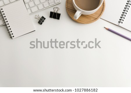 Flat lay, top view office table desk. Workspace with blank notepad, keyboard, office supplies, pencil, green leaf, and coffee cup on white background.