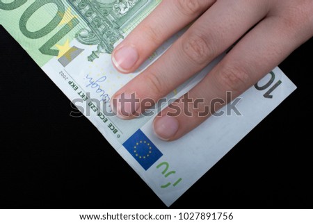 Hand holding 100 euro money  cash isolated on black background