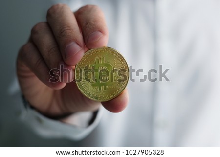 Hand holding golden Bitcoin virtual money.
