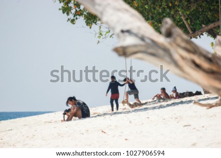 The blurred image of a woman taking a photo at a beautiful beach.