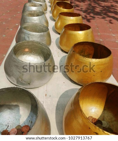 Coin in gold and silver monk bowl on the table 