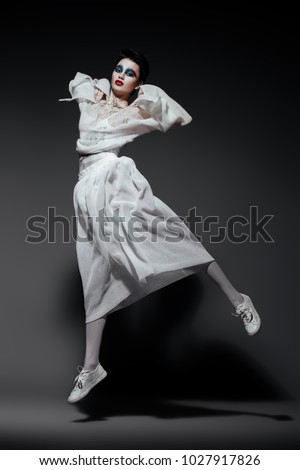 Beautiful female model in stylish clothes jumping over gray background. Beauty, fashion. Studio shot.