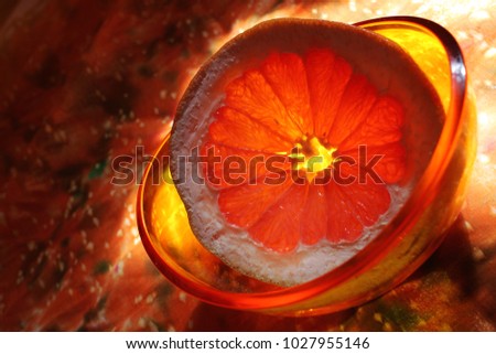Grapefruit cut off the ring in yellow transparent plate. Bright orange background