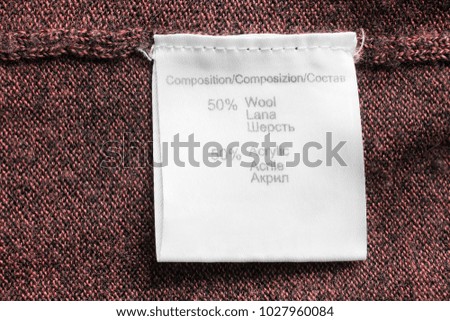 Fabric composition clothes label on brown knitted background closeup