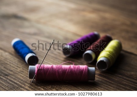 a sewing thread on a wooden background Royalty-Free Stock Photo #1027980613