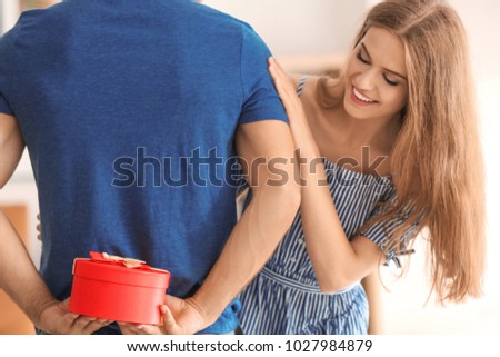 Man holding present for girlfriend behind his back at home