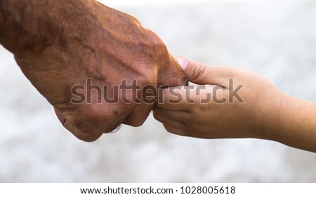 Young boy holding an old man's hand Royalty-Free Stock Photo #1028005618