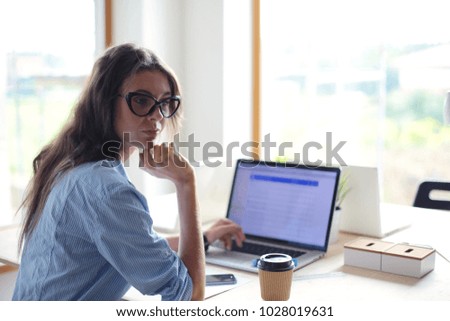 Young woman sitting in office table, looking at laptop computer screen . Young woman