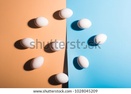Nine white easter eggs on blue and beige color background. Traditional food and holidays. Copy space. Easter decoration. 3D effect.
