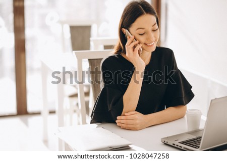 Business woman working with laptop in a white cafe