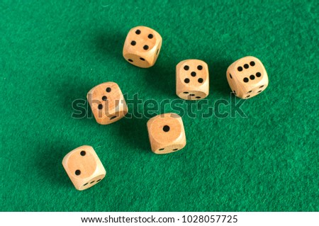 Wooden round corner dice six sided dots set for playing on dark green poker table felt cloth surface as background