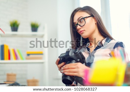 pretty young woman photographer with camera in office