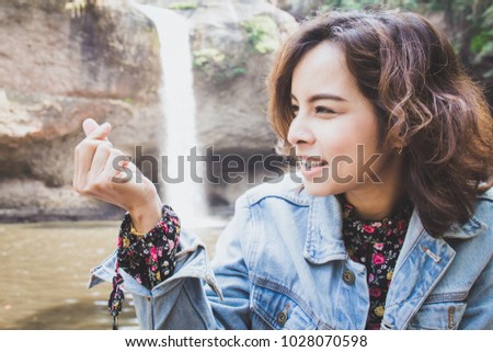Asian young woman making a heart shape with her hands in the natural waterfall thailand