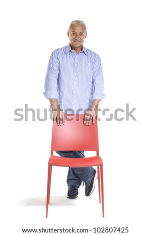 Senior man holding a red chair on white background.
