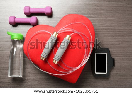 Gym stuff, phone and red heart on wooden background. Cardio training concept