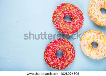 Multicolored donuts close-up on a blue wooden background. Delicious dessert.