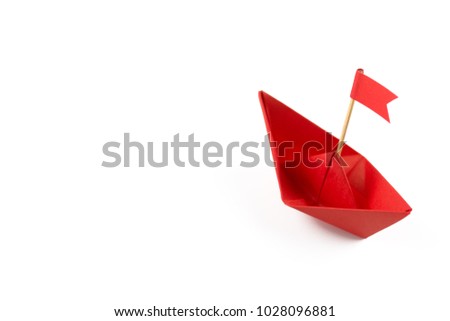 Red paper ship and red flag isolated on white background. Paper craft and origami. Close up. 