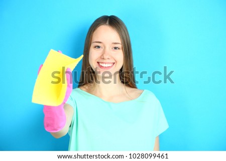 A smiling cleaning lady in rubber gloves with a viscose napkin on a blue background.