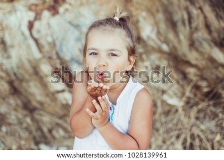 Portrait of a cute lovely little girl sends an air kiss