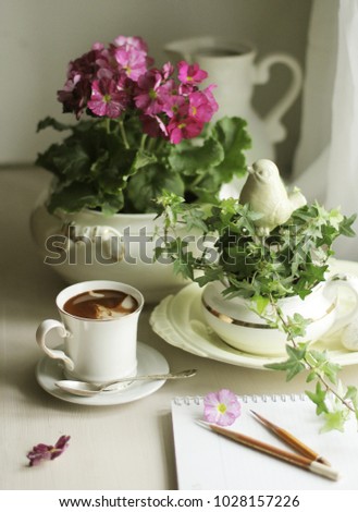 Home flowers in white, vintage kitchenware, coffee in a White porcelain Cup with a gold rim and a calendar of garden work on a white table
